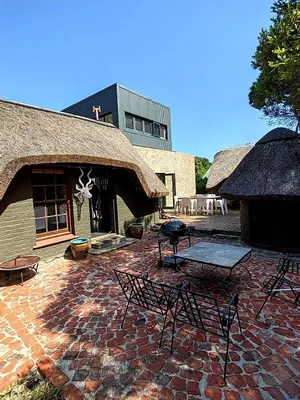 a patio with chairs and tables and a building at Bobbejaanskloof in Bettyʼs Bay