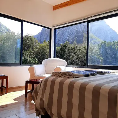a bedroom with a bed and large windows with a view at Bobbejaanskloof in Bettyʼs Bay