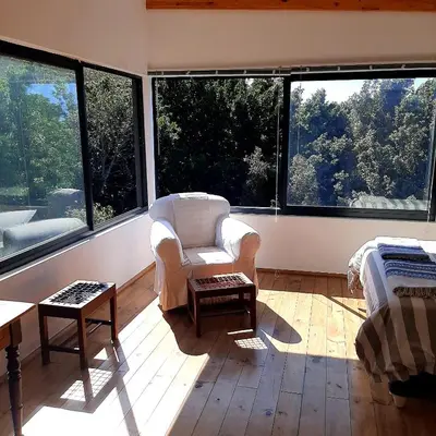 a living room with a chair and large windows at Bobbejaanskloof in Bettyʼs Bay