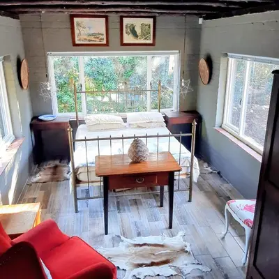 a room with a bed and a table and a window at Bobbejaanskloof in Bettyʼs Bay