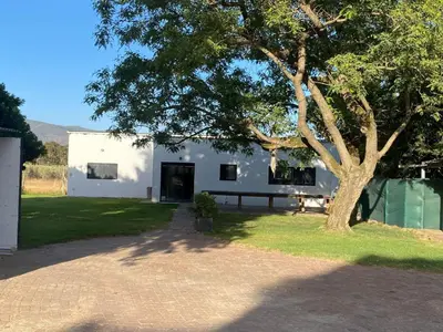 a white building with a tree in front of it at Magents Farm Guesthouse in Paarl