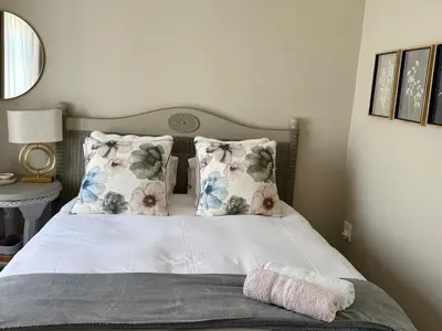 a bed with white sheets and pillows in a bedroom at Sipres Garden in Durbanville