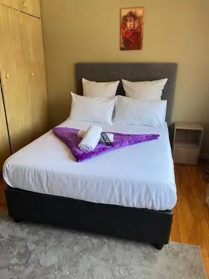 a bed with a purple blanket on top of it at Ridah's Accomodation in Bellville