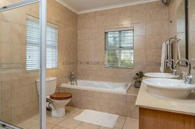 a bathroom with a tub and a toilet and a sink at Cheerful 4 bedroom home with pool & wonderful view in Somerset West
