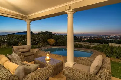 a patio with wicker chairs and a swimming pool at Cheerful 4 bedroom home with pool & wonderful view in Somerset West