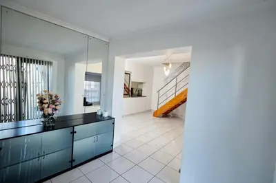 a living room with a blue cabinet and a staircase at Townhouse in Bloubergstrand in Cape Town
