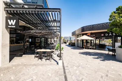 an outdoor patio with tables and chairs and umbrellas at 510 Riverlands - Lux 1 bedroom Apartment in Cape Town