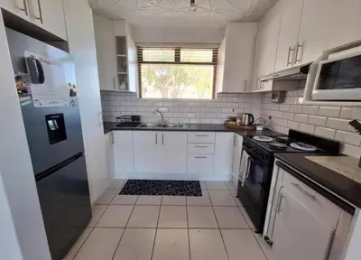 a kitchen with white cabinets and a black refrigerator at Villa d'aqua in Cape Town