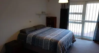 a bedroom with a bed in a room with windows at Villa d'aqua in Cape Town