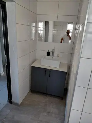 a bathroom with a sink and a person in a mirror at Rihla Residences - Hanbury Road in Cape Town