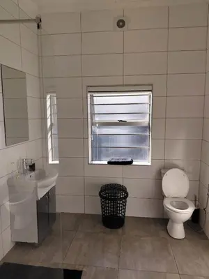 a bathroom with a toilet and a sink and a window at Rihla Residences - Hanbury Road in Cape Town