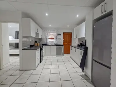 a large kitchen with white cabinets and a tile floor at Gulls Nest in Hermanus