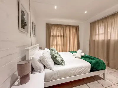 a bedroom with a bed with white sheets and pillows at Gulls Nest in Hermanus