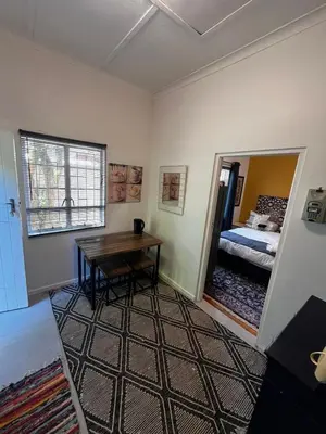 a room with a table and a bed and a window at Central Eclectic Studio by ARPA Hospitalities in Stellenbosch