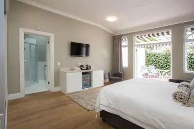 a bedroom with a bed and a tv on the wall at Summerwood Guest House in Stellenbosch