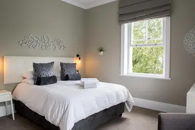 a bedroom with a large white bed with a window at Summerwood Guest House in Stellenbosch