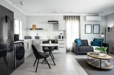 a kitchen and living room with a table and a couch at CAG The Alxndr Stellenbosch in Stellenbosch