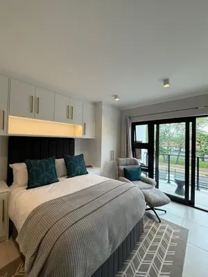 a bedroom with a large bed and a chair at CAG The Alxndr Stellenbosch in Stellenbosch