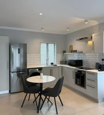 a kitchen with a table and chairs in it at CAG The Alxndr Stellenbosch in Stellenbosch