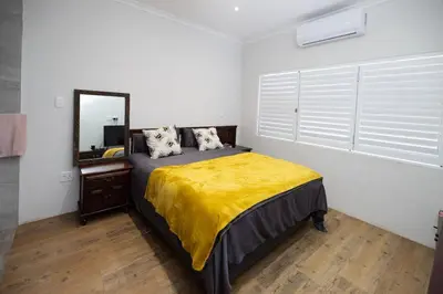 a bedroom with a bed with a yellow blanket at Garden Pool Manor House in Kuilsrivier