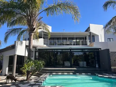 a house with a swimming pool and a palm tree at 2 on Aurora Island in Durbanville
