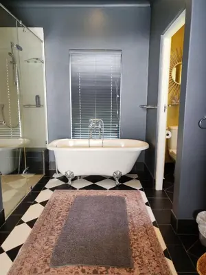 a bath tub in a bathroom with a black and white floor at Franschhoek Guest Suite in Franschhoek