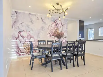 a dining room with a table and chairs with a flower mural at 12 Sleeper Luxury Villa Chaffinch in Cape Town