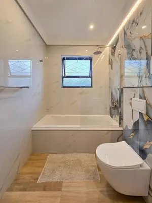a white bathroom with a tub and a toilet at 12 Sleeper Luxury Villa Chaffinch in Cape Town