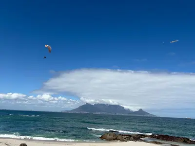 a kite flying in the sky over the ocean at Home Away From Home 6 minutes away from beach in Cape Town
