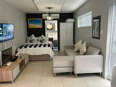 a bedroom with a bed and a couch and a tv at Home Away From Home 6 minutes away from beach in Cape Town