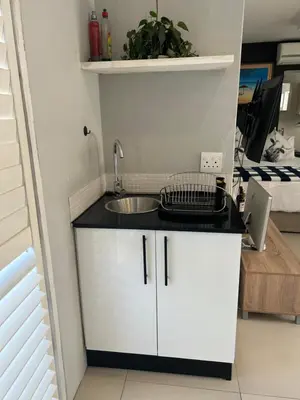 a small kitchen with a sink and a bed at Home Away From Home 6 minutes away from beach in Cape Town