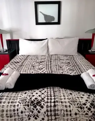 a bedroom with a black and white bed with two lamps at Le Bay Lodge in Gordonʼs Bay