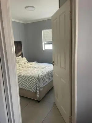 a bedroom with a bed and an open door at Blouberg Beach Gem 5 Min Walk in Cape Town