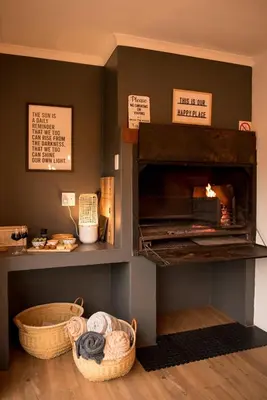 a room with a fireplace with baskets on the floor at CalTye On Sea in Hermanus