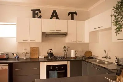a kitchen with white cabinets and a sink and an oven at CalTye On Sea in Hermanus