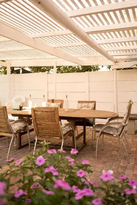 a wooden table and chairs under a white pergola at CalTye On Sea in Hermanus
