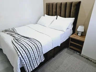 a bedroom with a white bed with a wooden headboard at Evernice Guest House in Cape Town