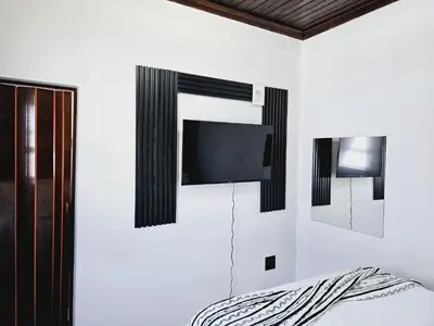 a bedroom with a tv on the wall and a bed at Evernice Guest House in Cape Town