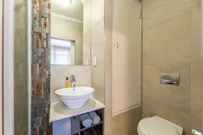 a bathroom with a sink and a toilet and a shower at Portifino on lake 221 The Island Club in Cape Town