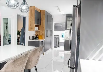 a kitchen with a white counter and chairs in it at Sukoluhle Guest House in Cape Town