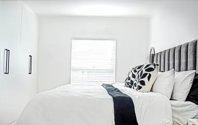 a white bedroom with a large bed and a window at Sukoluhle Guest House in Cape Town