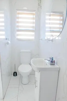 a white bathroom with a toilet and a sink at Sukoluhle Guest House in Cape Town