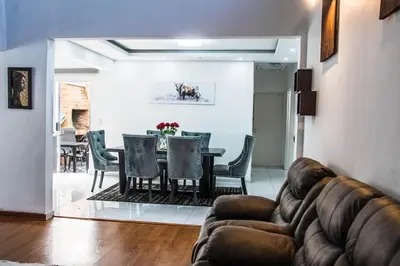 a living room with a couch and a table and chairs at Sukoluhle Guest House in Cape Town