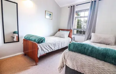 a bedroom with two beds and a window at Die Steenbras in Fisherhaven