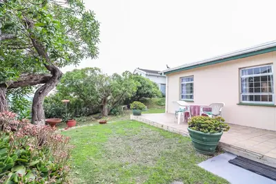 a patio with a table and chairs in a yard at Die Steenbras in Fisherhaven