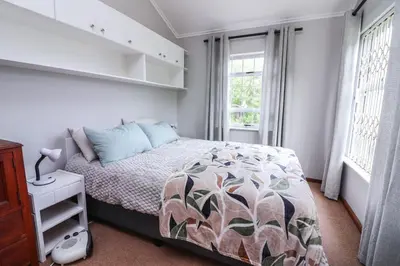 a bedroom with a bed and two windows at Die Steenbras in Fisherhaven