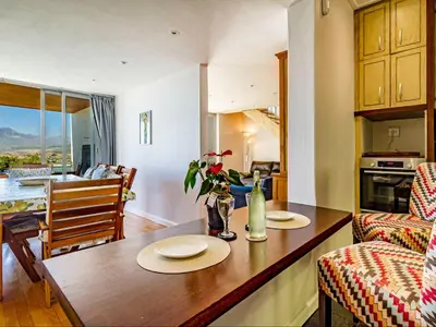 a kitchen and living room with a table with plates on it at 5 Suikerbossie in Gordonʼs Bay
