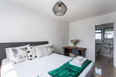 a white bedroom with a bed and a bathroom at Knightsbridge 702W by CTHA in Cape Town