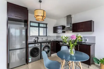 a kitchen with a table and a washer and dryer at Knightsbridge 702W by CTHA in Cape Town