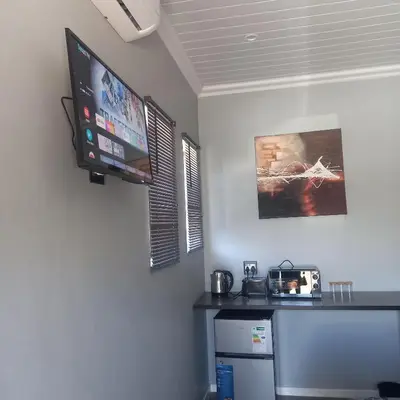 a room with a tv on the wall and a refrigerator at Forbes on Zastron in Cape Town